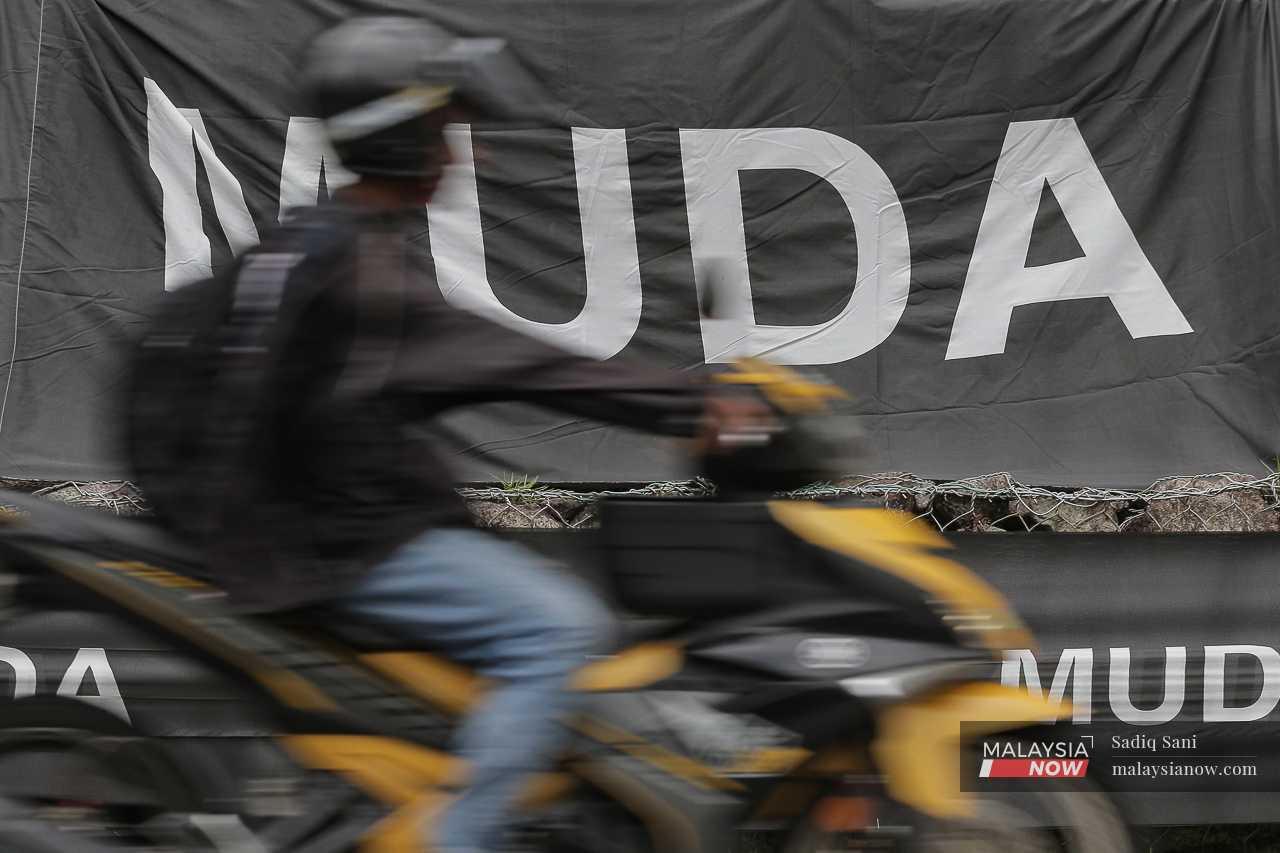 A motorcyclist passes the flags of youth-based party Muda in Bukit Antarabangsa. 