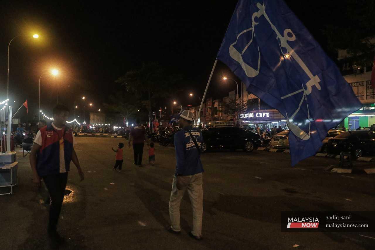 A man carries a Barisan Nasional flag during a campaign event in Semenyih. 