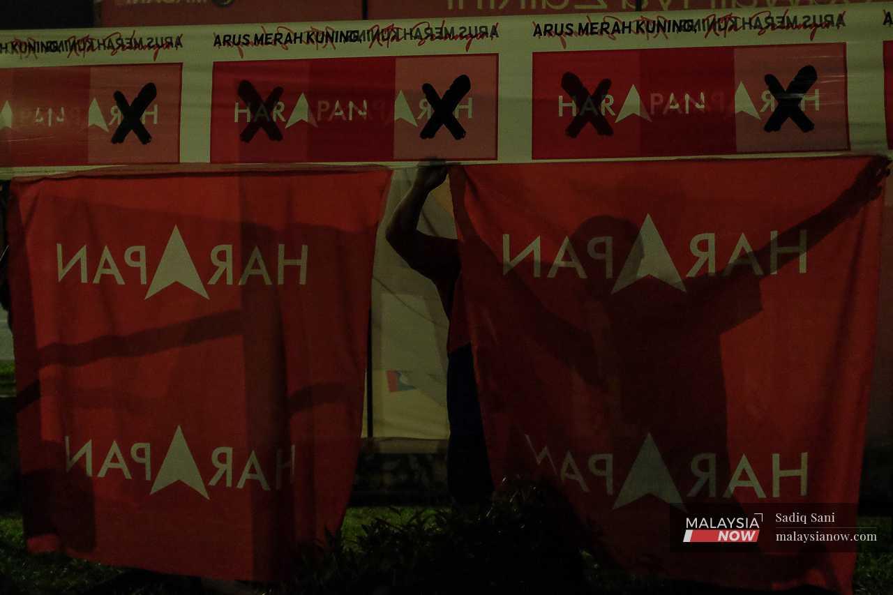 Pakatan Harapan volunteers are silhouetted against party flags in Taman Melawati, Hulu Kelang. 