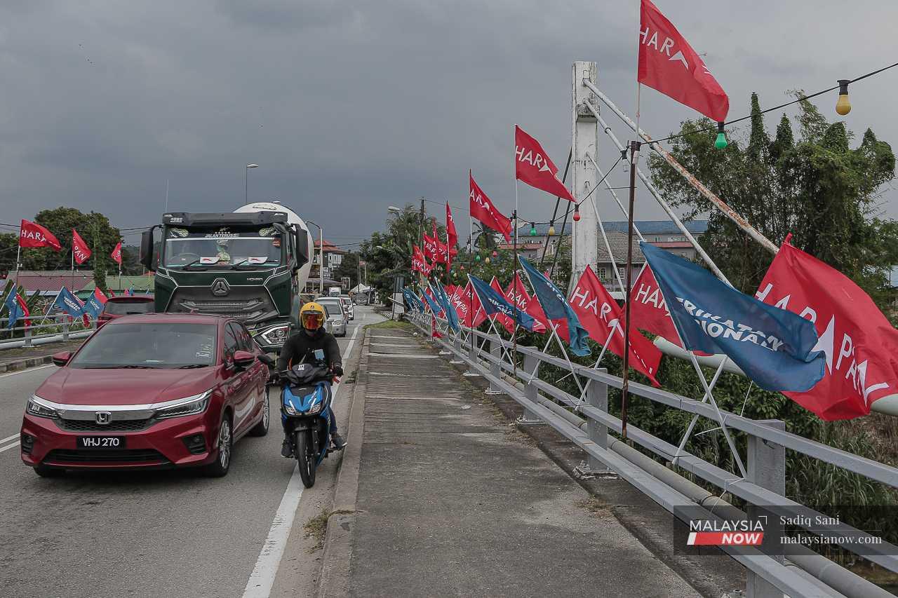 Vehicles cross a bridge in Sungai Ramal hung about with party flags.