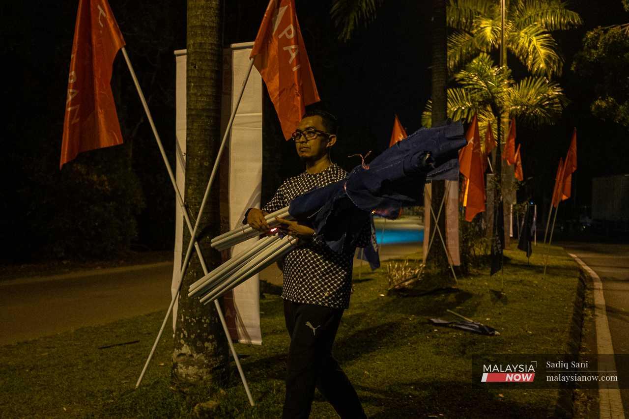 A volunteer carries an armful of flags late at night to be put up in Bangi, Selangor.