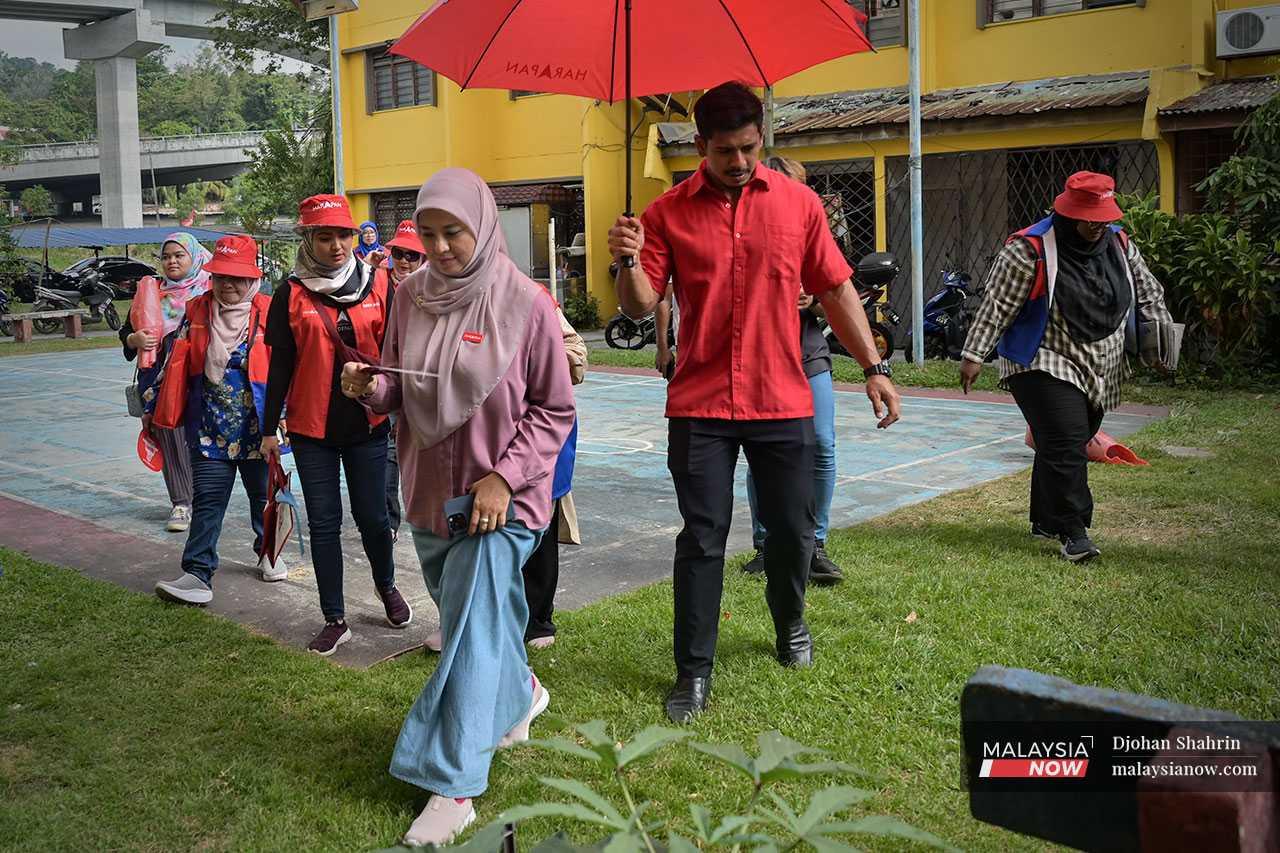 Juwairiya makes her way through the drizzle from block to block of the low-cost apartment in Keramat.