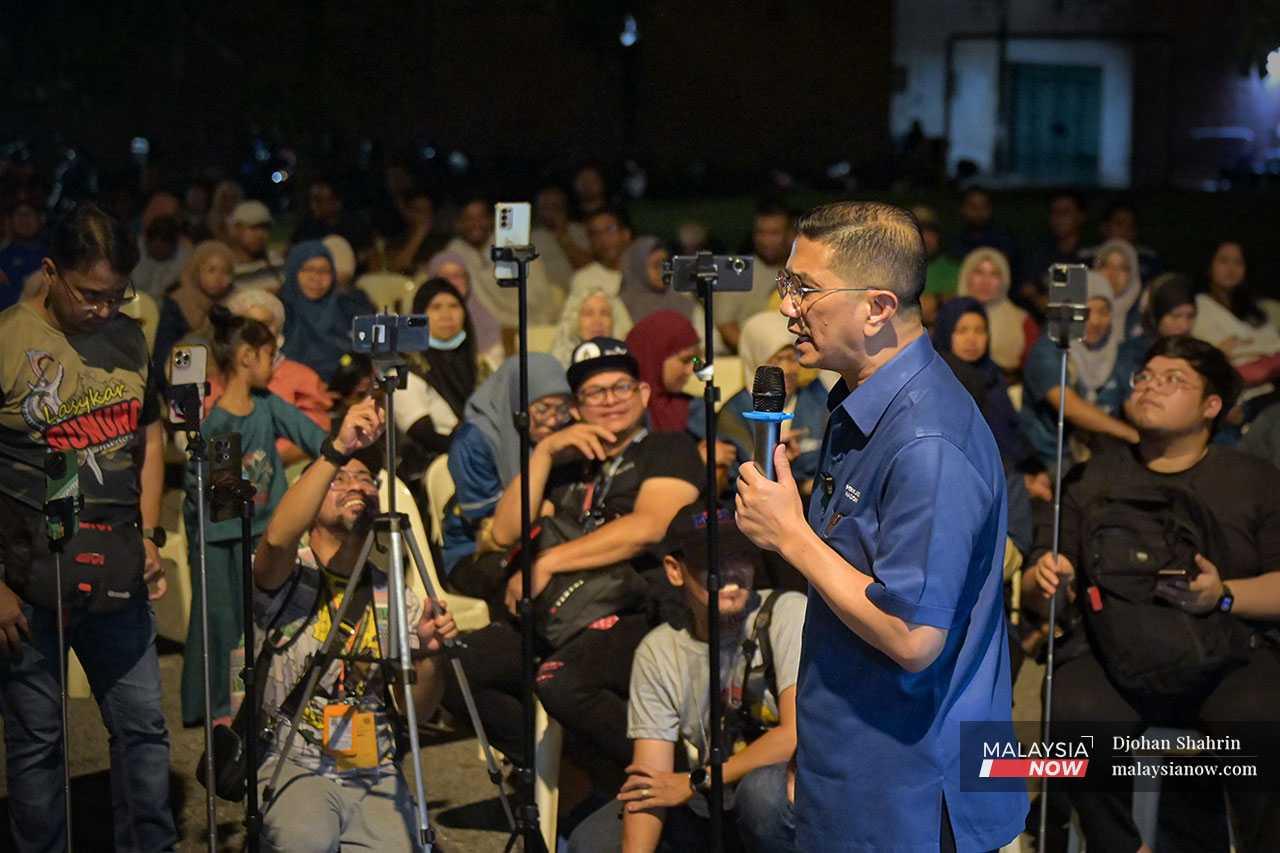 Azmin speaks to the crowd, his every word recorded and broadcast by the row of camera phones before him. 