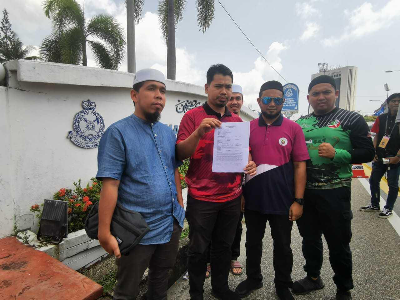 Mohd Hilmi Jusoh (dua dari kiri) memegang salinan laporan polisnya yang dibuat di Ibu Pejabat Polis Kuala Terengganu, 8 Ogos.
