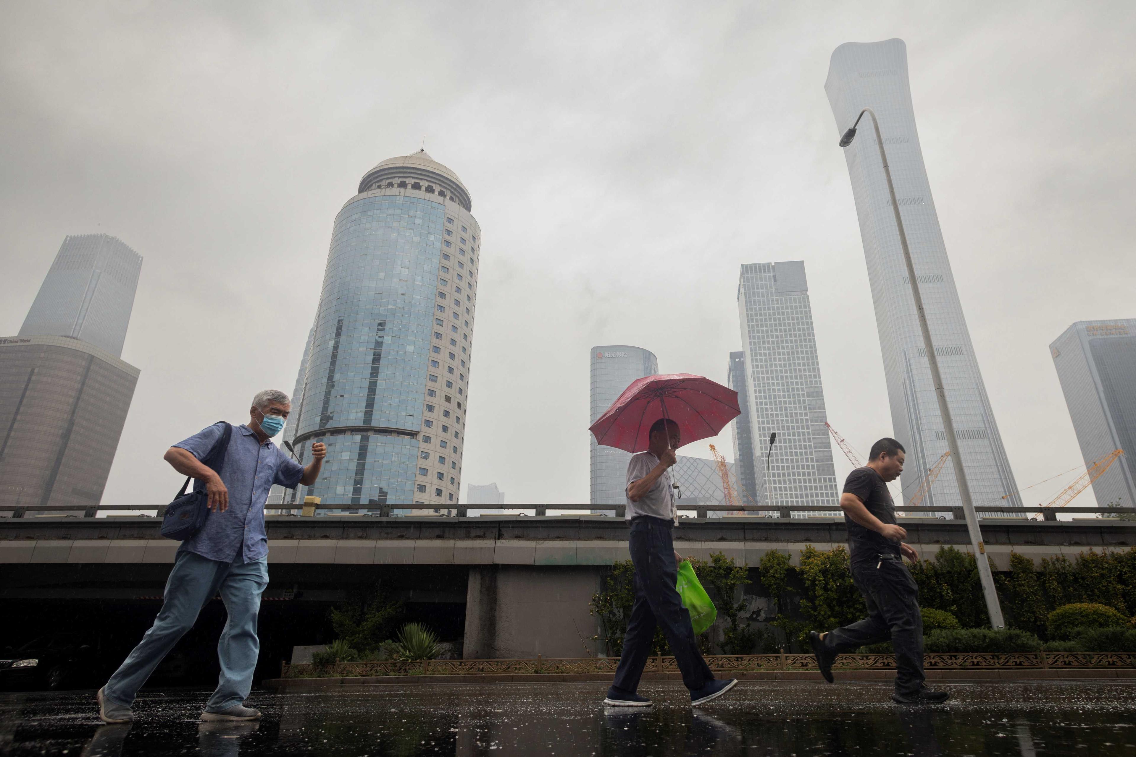 People walk in the Central Business District on a rainy day in Beijing, China, July 12. Photo: Reuters
