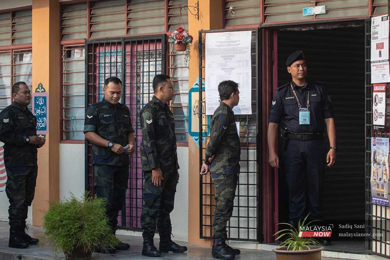 Anggota polis beratur bagi menunggu giliran untuk mengundi di luar bilik mengundi. 