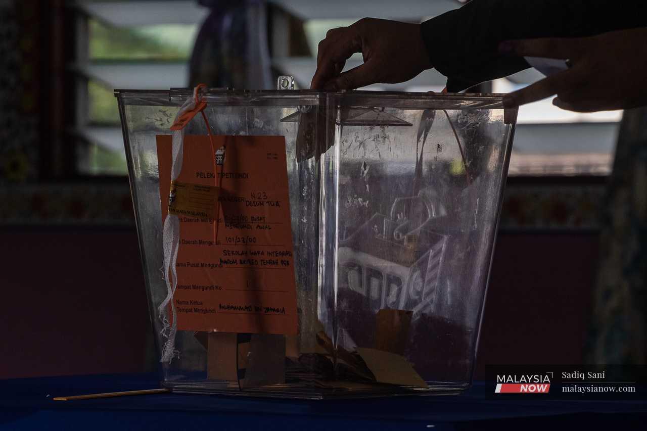 An officer drops his ballot paper into the box for votes at Markas Briged Tengah Pasukan Gerakan Am in Cheras.