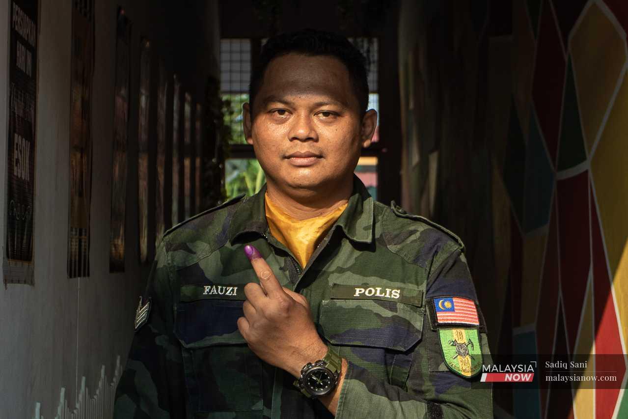 Seorang lagi pegawai polis menunjukkan jarinya yang berlumuran dengan dakwat kekal selepas selesai mengundi.