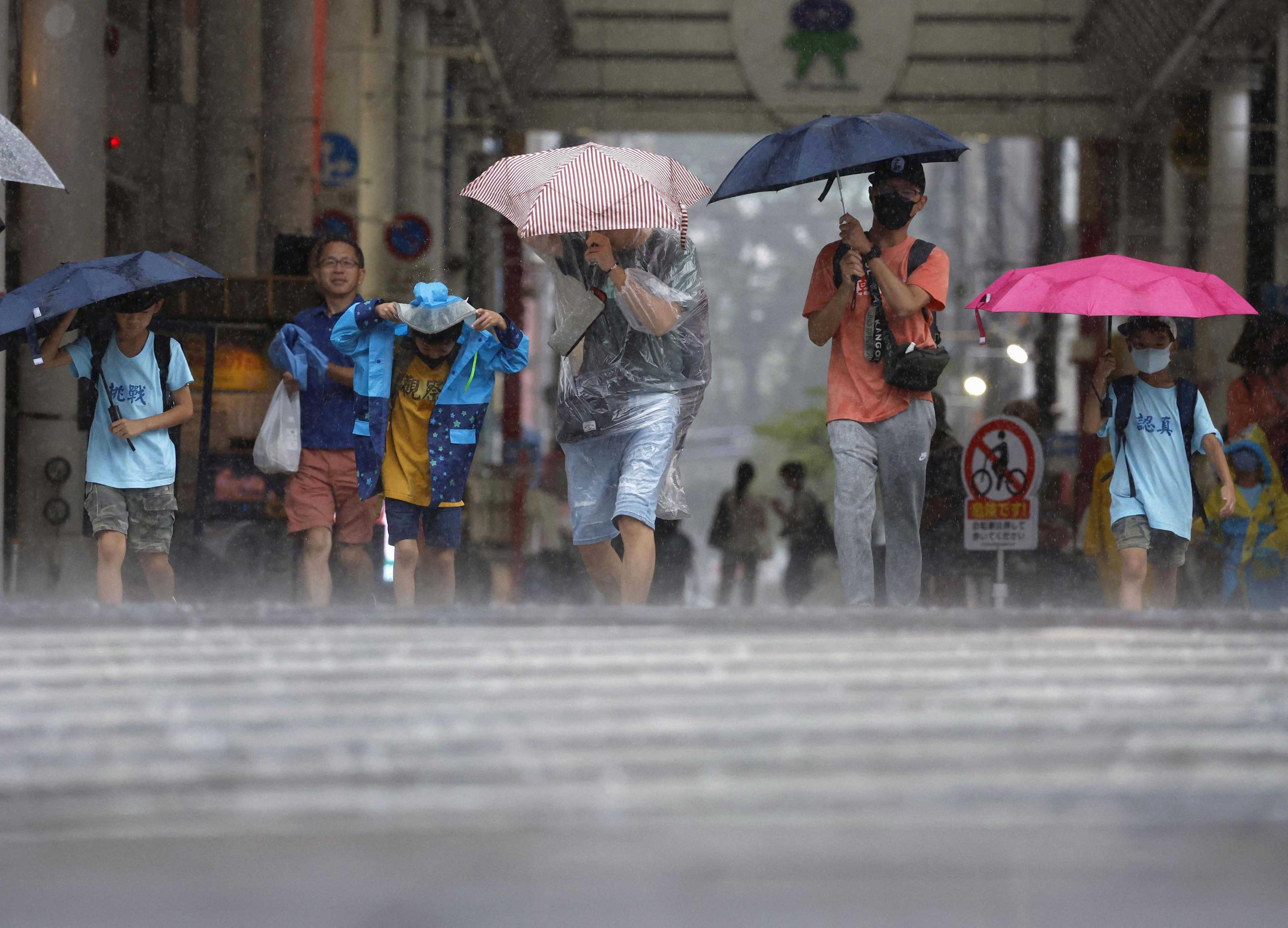 Passersby walk in a heavy rain and wind caused by Typhoon Khanun in Kagoshima on Japan's third-largest island Kyushu, Aug 8, in this photo taken by Kyodo. Photo: Reuters