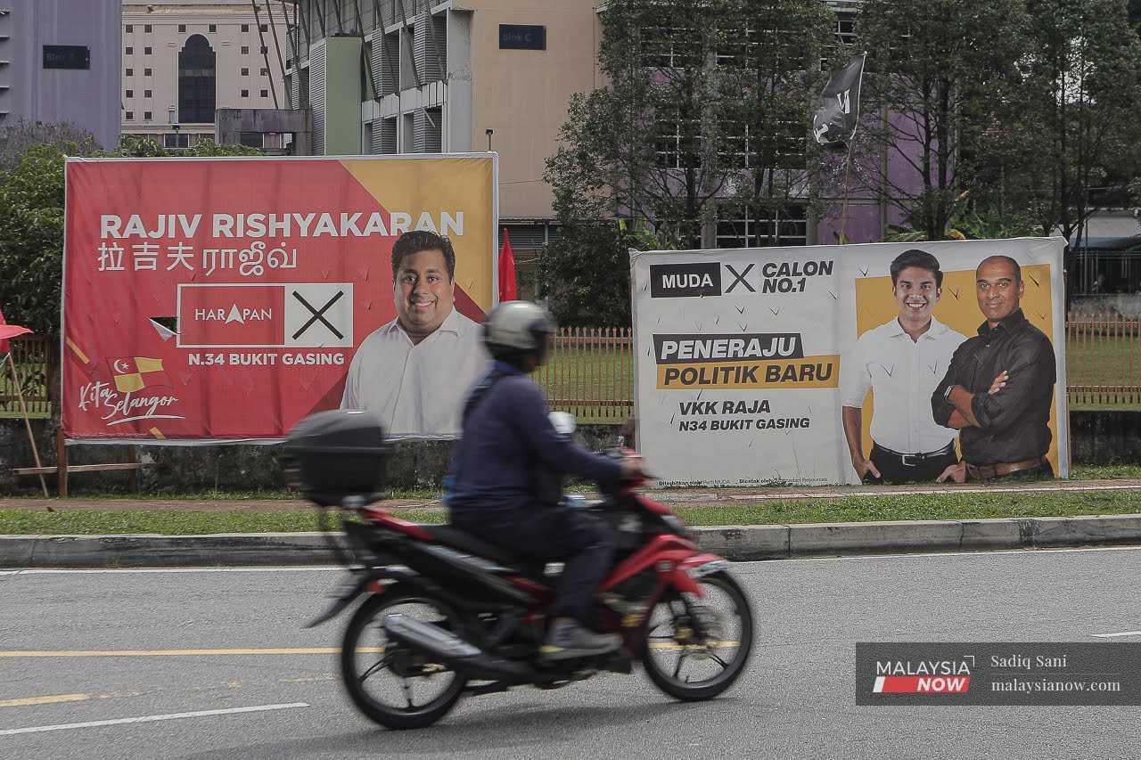 A motorcyclist passes banners featuring Pakatan Harapan's Bukit Gasing assemblyman Rajiv Rishyakaran and Muda candidate VKK Raja in Bukit Gasing, Petaling Jaya.