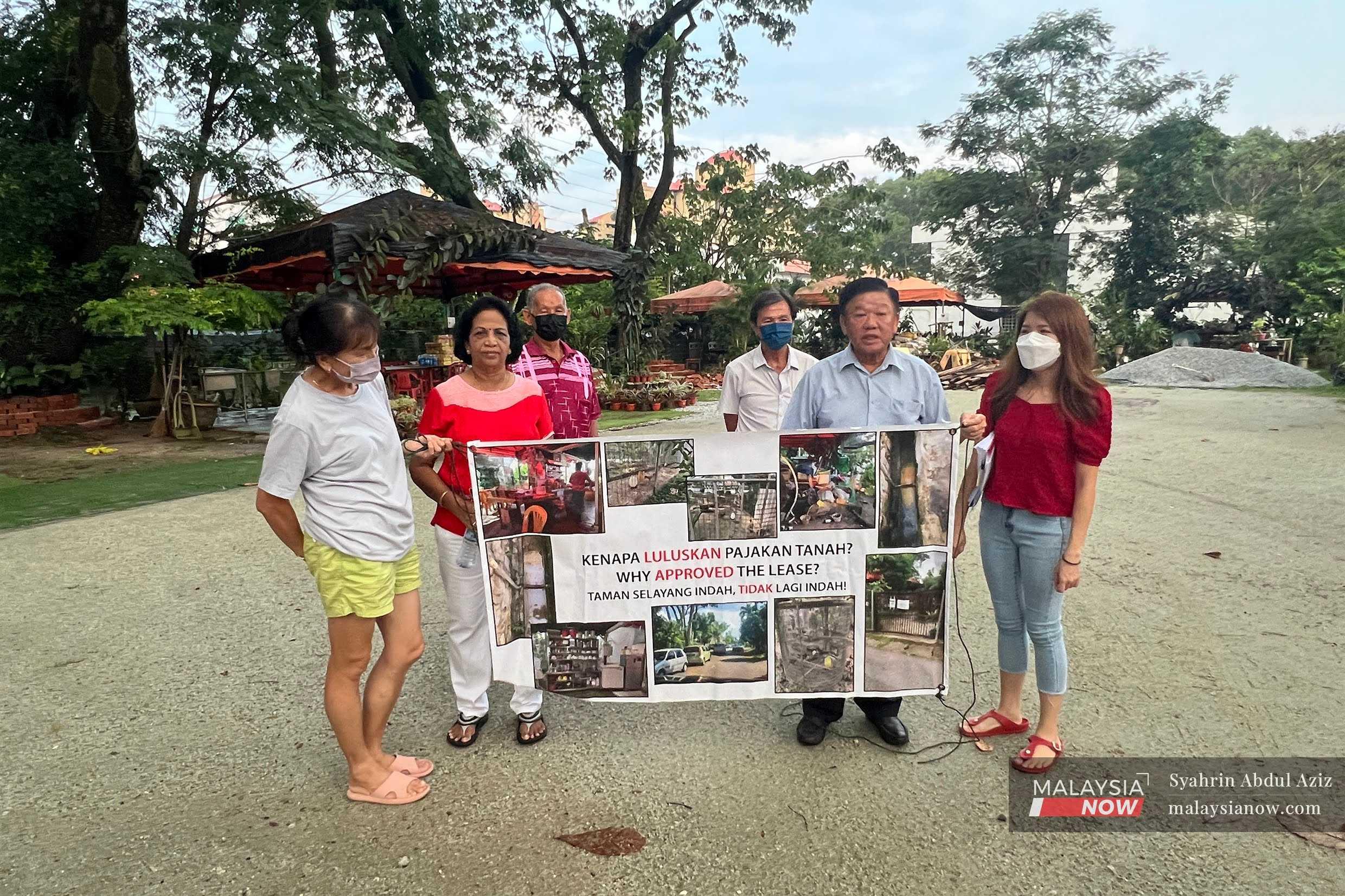 Residents of Taman Selayang Indah hold up a poster questioning the lease given for a plot of land in their neighbourhood.