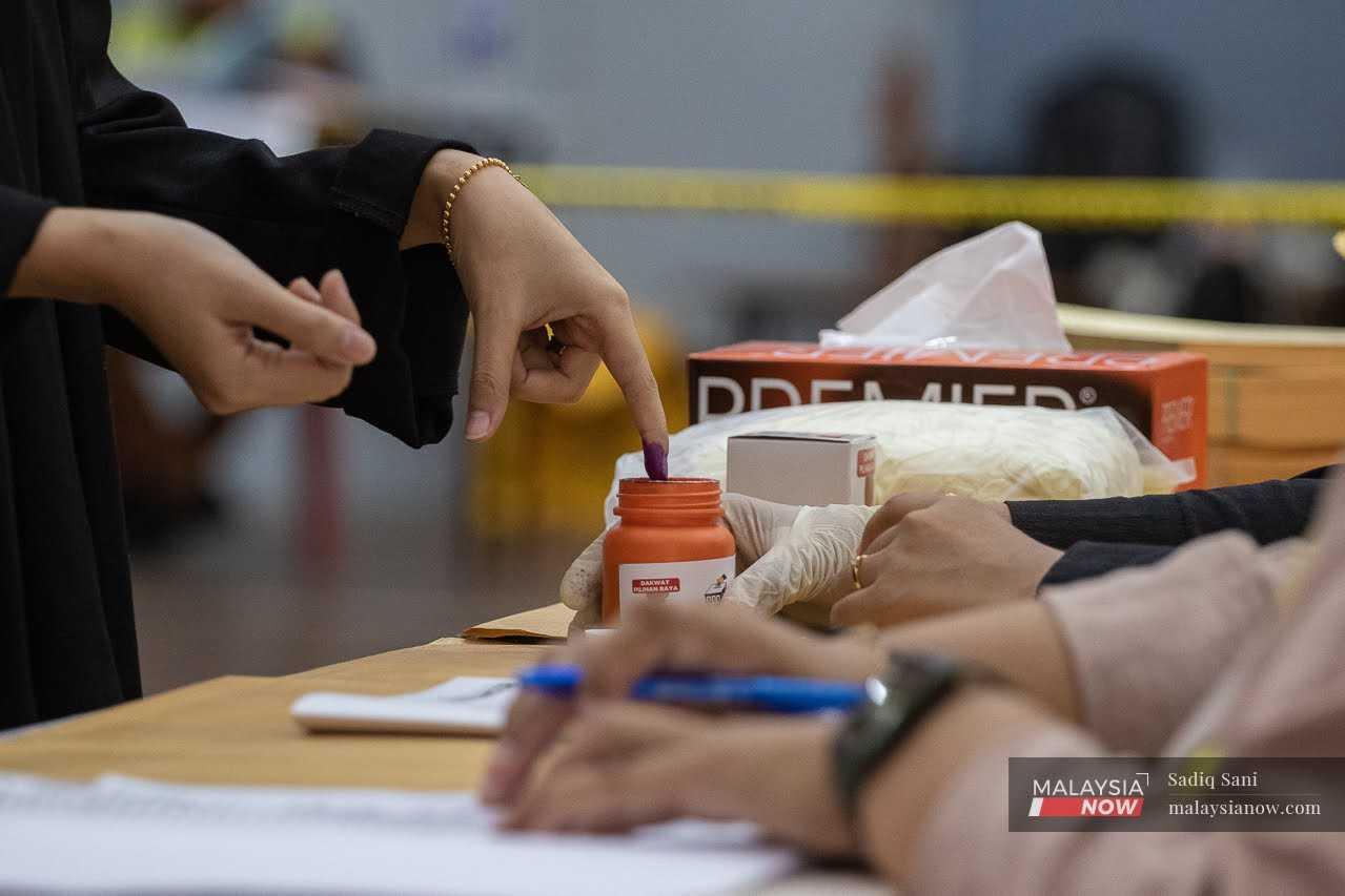 A voter has her finger marked with indelible ink before casting her vote for the Selangor election in Klang, Aug 12.