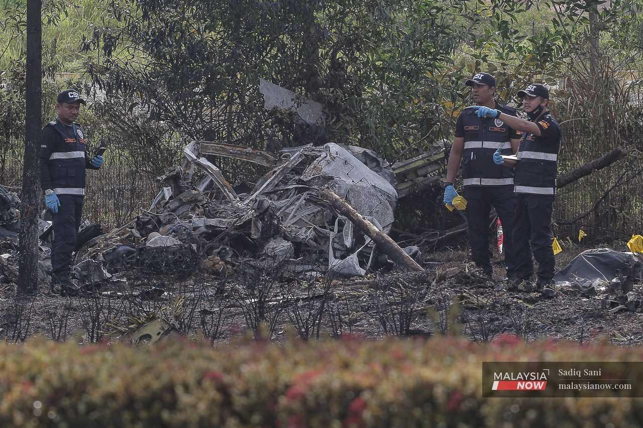 Forensic officers stand next to the plane wreckage in Elmina, Shah Alam, Aug 17.