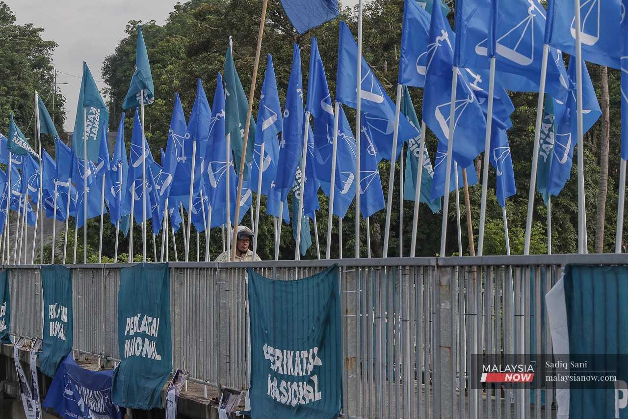 A motorcyclist crosses a bridge in Dengkil decorated with the flags of Barisan Nasional and Perikatan Nasional, ahead of the state election on Aug 12.