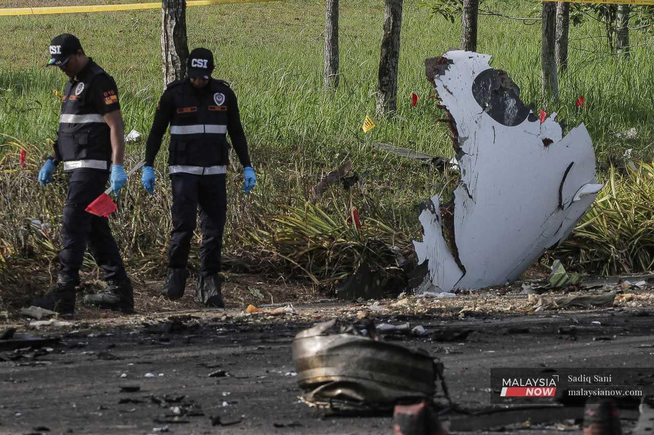 Investigative personnel make their way through debris at the scene of the plane crash in Elmina, Shah Alam, Aug 17.