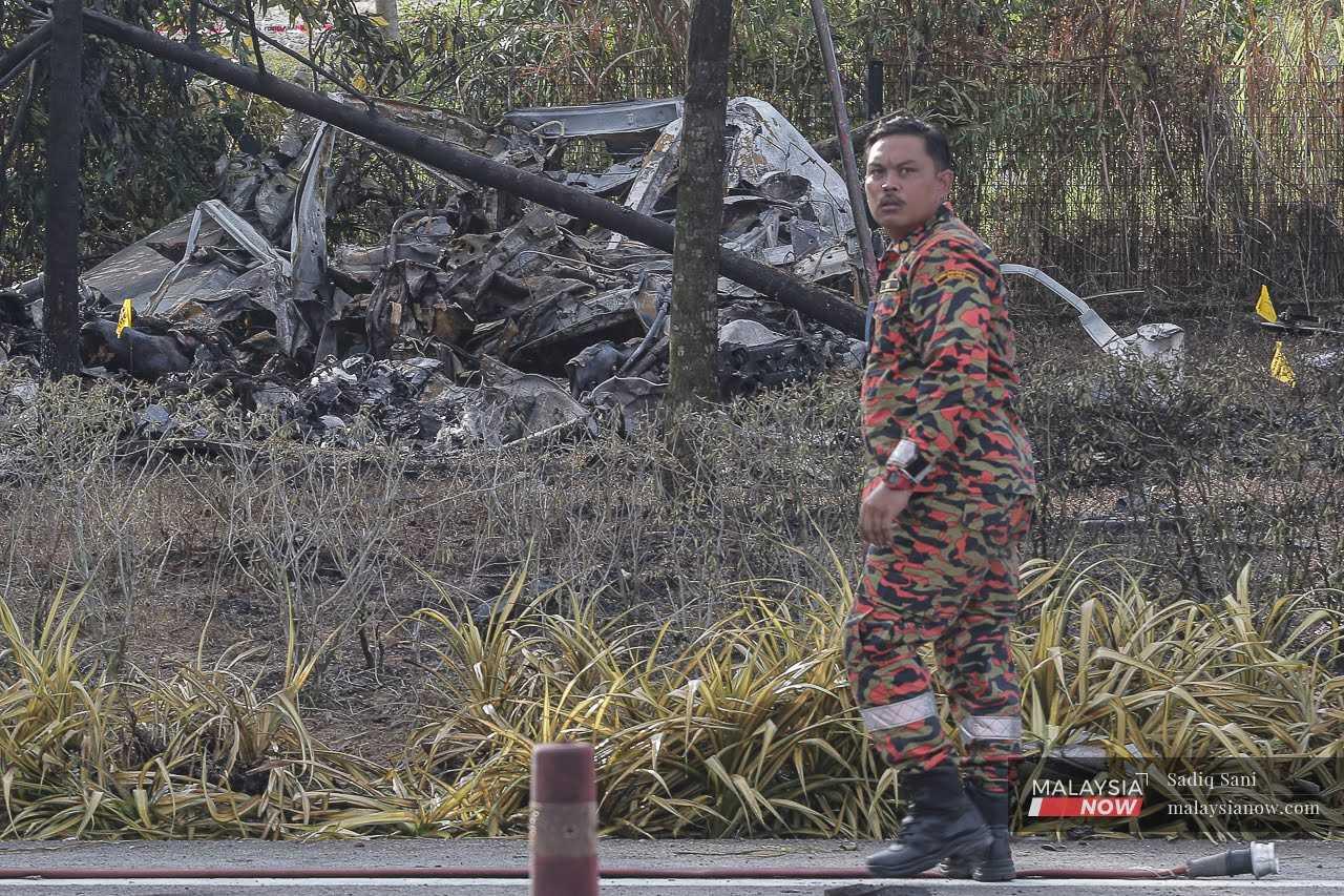 A member of the fire and rescue department inspects the crash site of a plane in Elmina, Shah Alam, Aug 17.