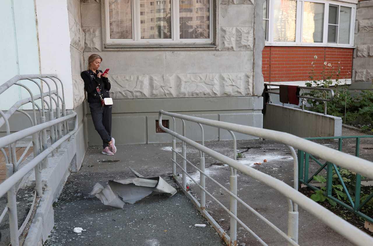 A woman checks her phone next to debris, following a reported drone attack in Krasnogorsk, Russia, Aug 22. Photo: Reuters