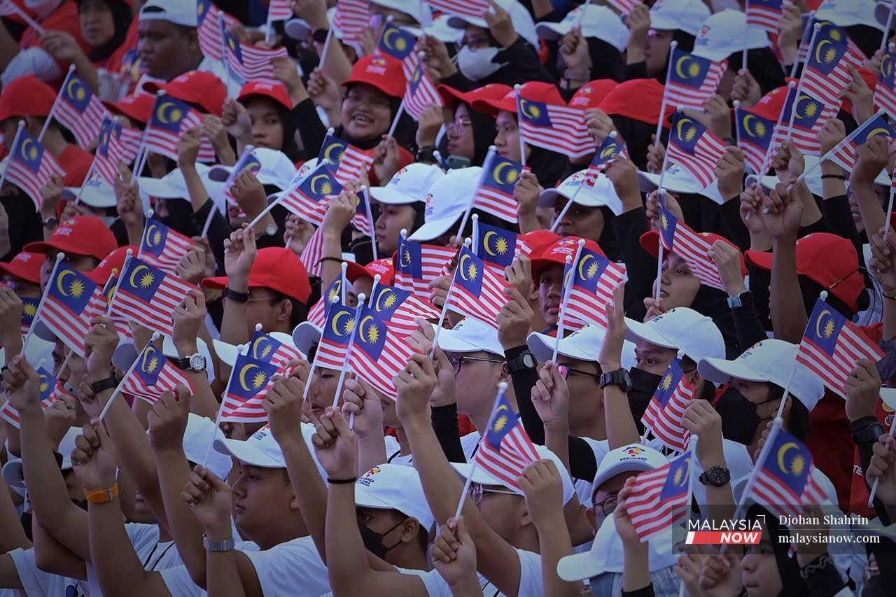 Participants wave the Jalur Gemilang during the parade to celebrate Merdeka Day in Dataran Merdeka, Kuala Lumpur, Aug 31, 2022.