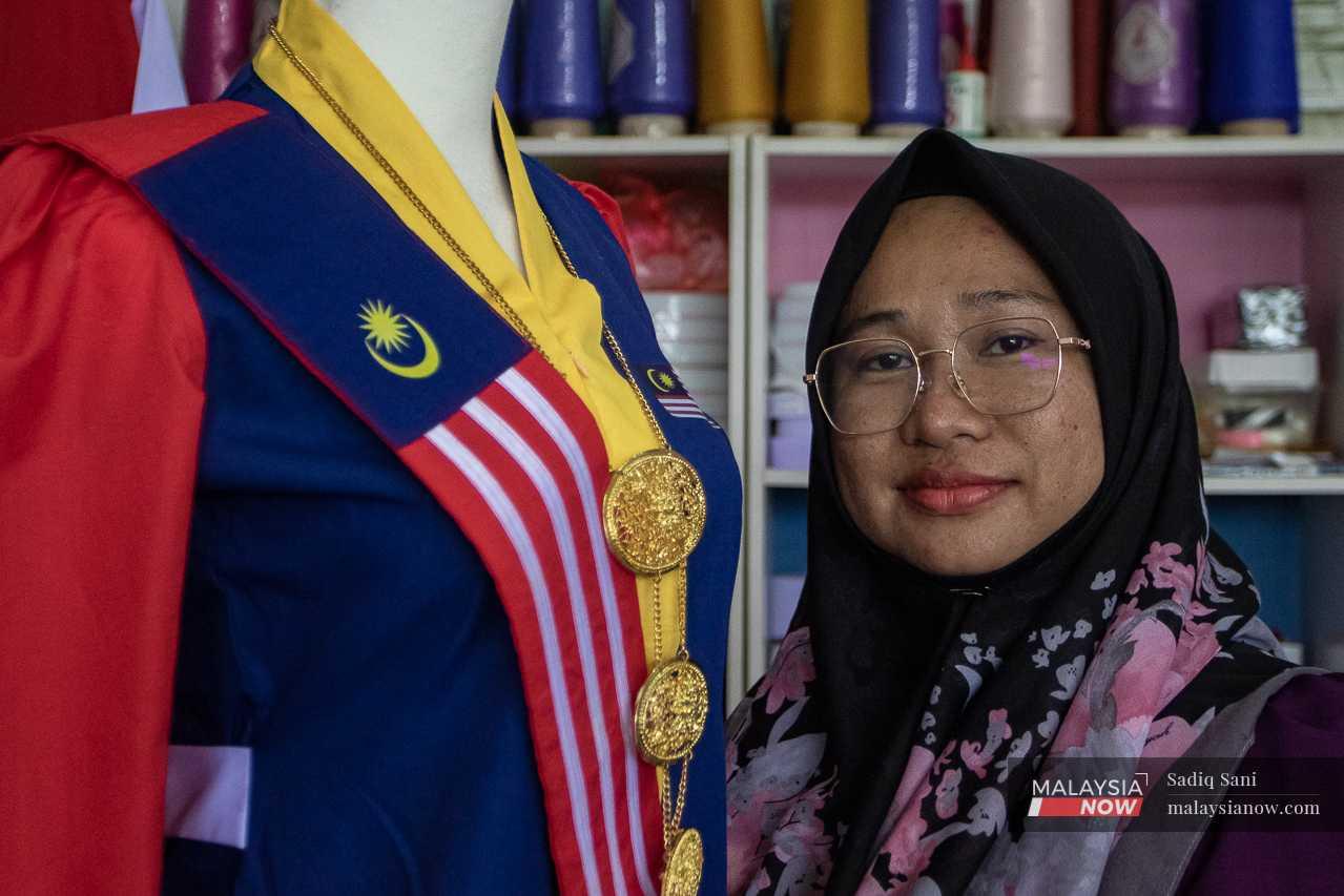 Helmaliza proudly stands next to her Jalur Gemilang kebaya at her tailor shop in Klebang Restu, Ipoh.