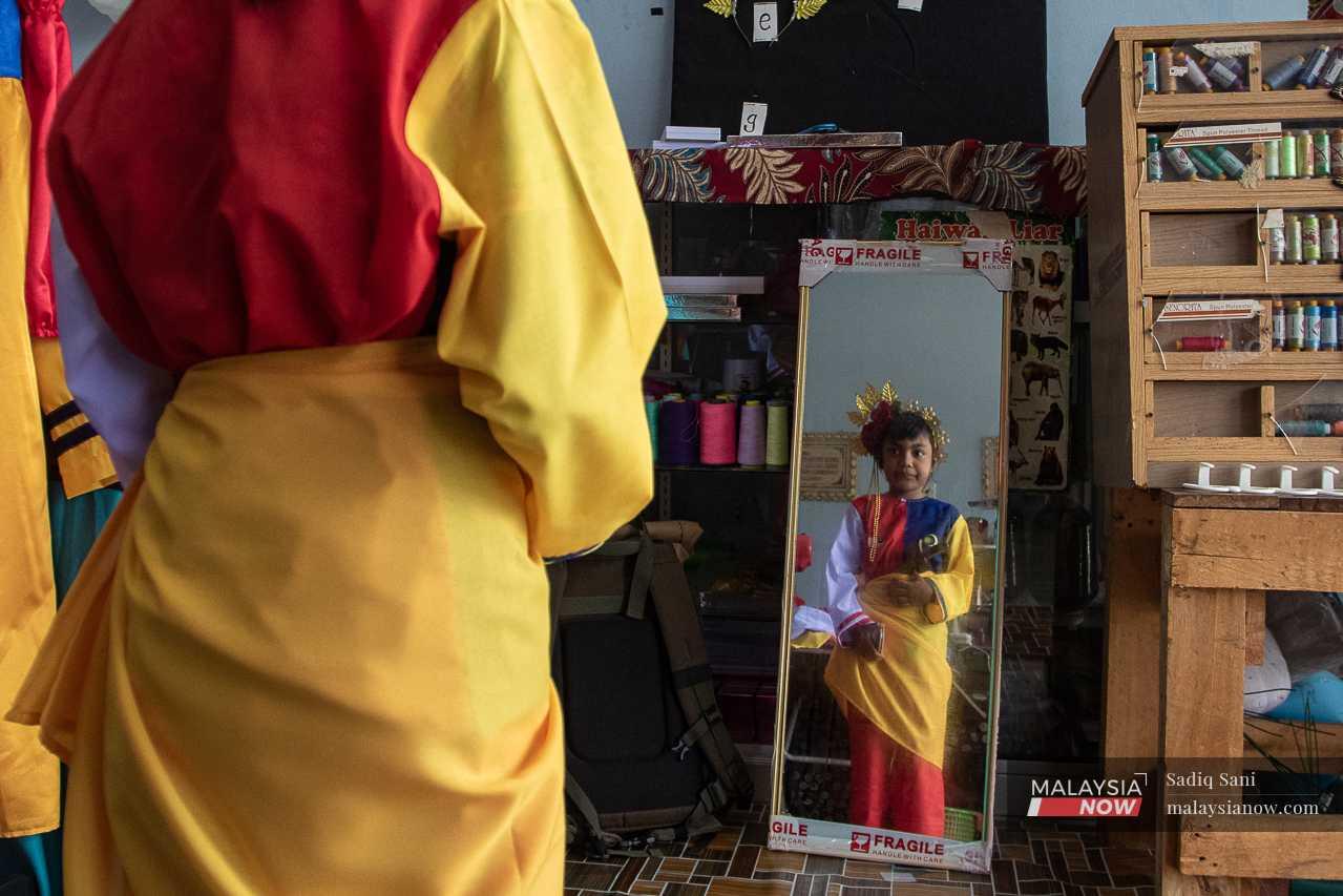 6-year-old Nur An'nissa Humaira, who is preparing for a Merdeka parade at her school, inspects her costume in front of a mirror.