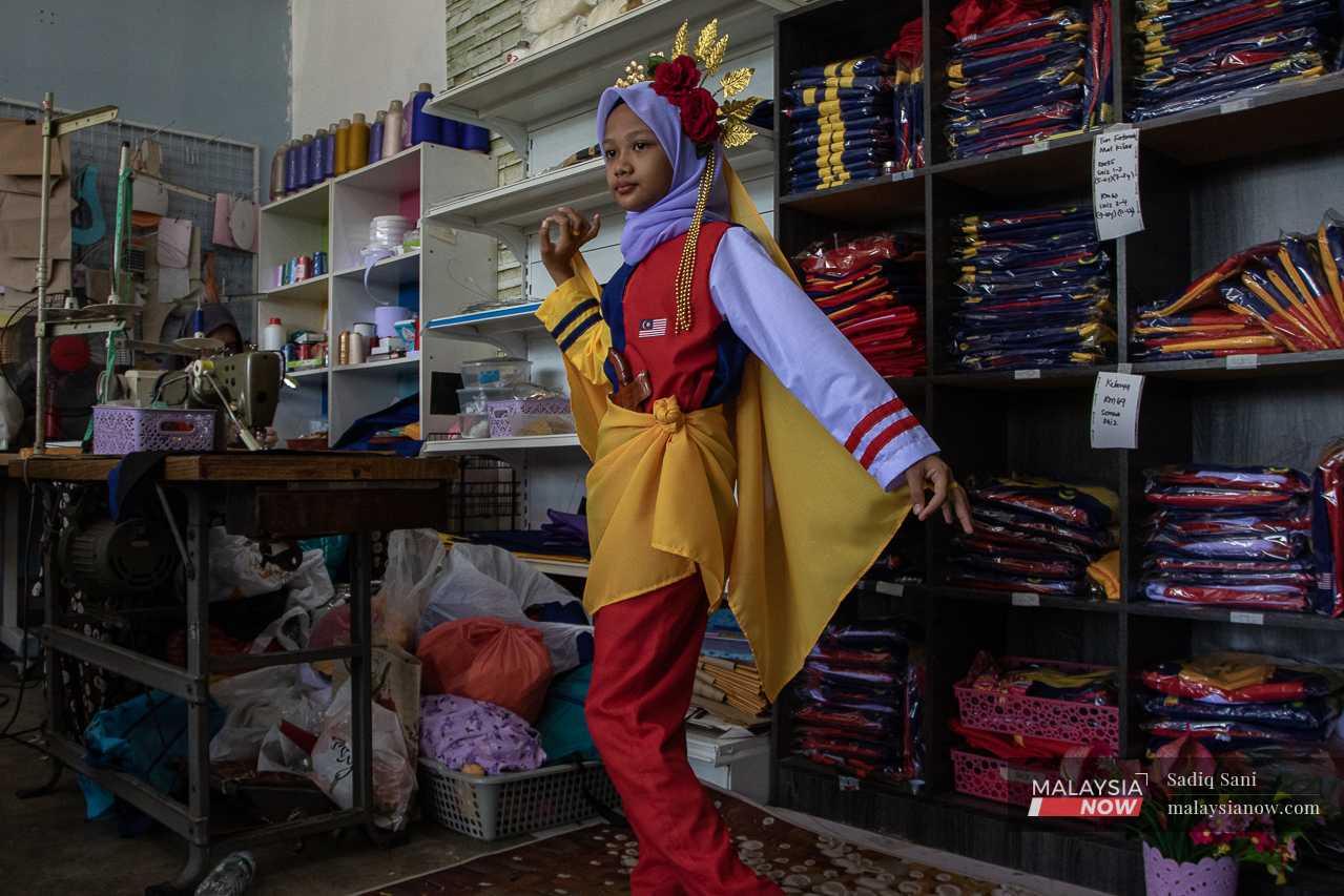 Zahra strikes a pose in Helmaliza's Tun Fatimah-themed Jalur Gemilang costume at her tailor shop.