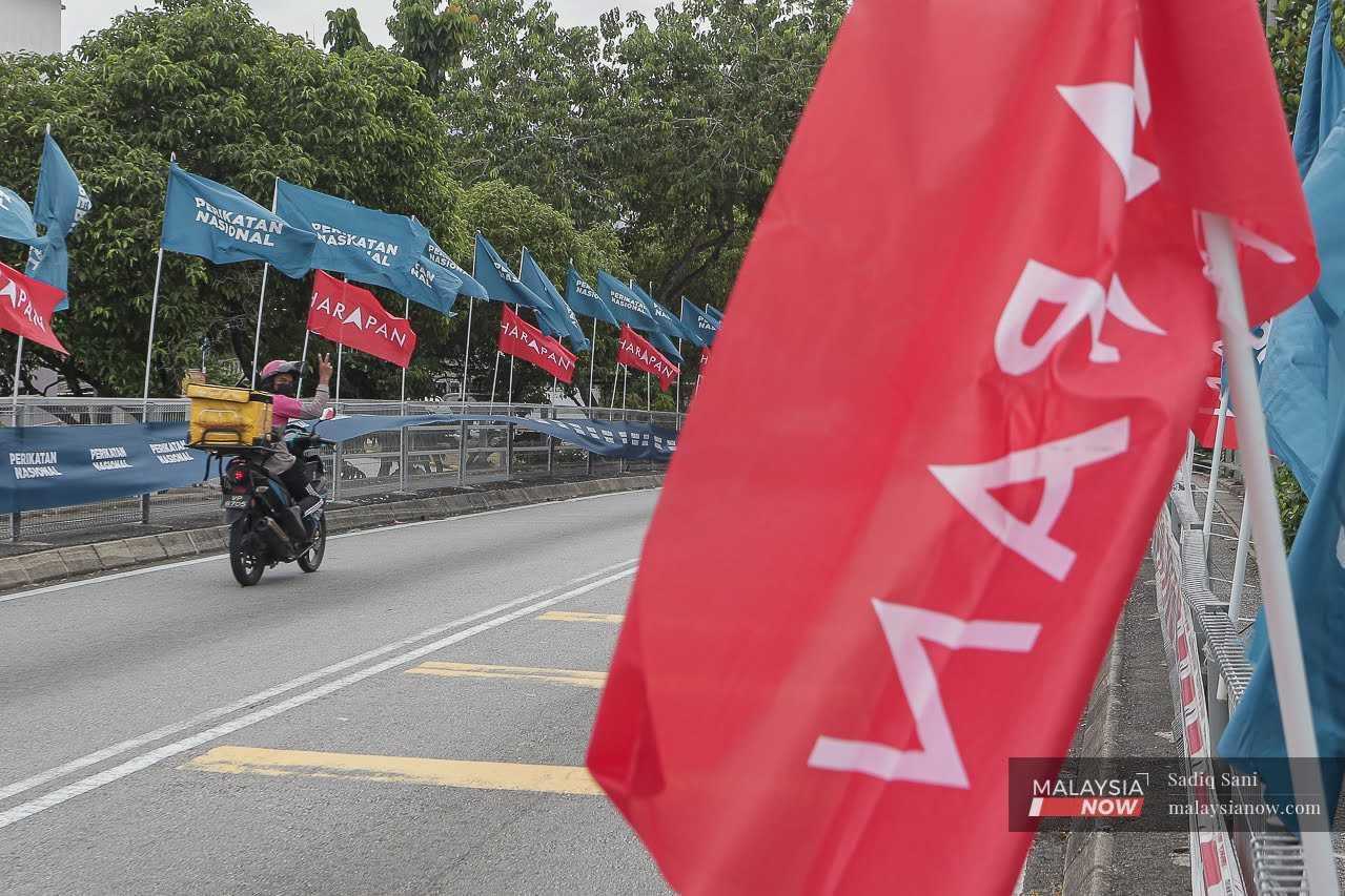 Seorang penghantar makanan sempat memberi isyarat ketika melalui jalan di Ampang yang dihiasi dengan bendera Perikatan Nasional dan Pakatan Harapan pada 3 Ogos.