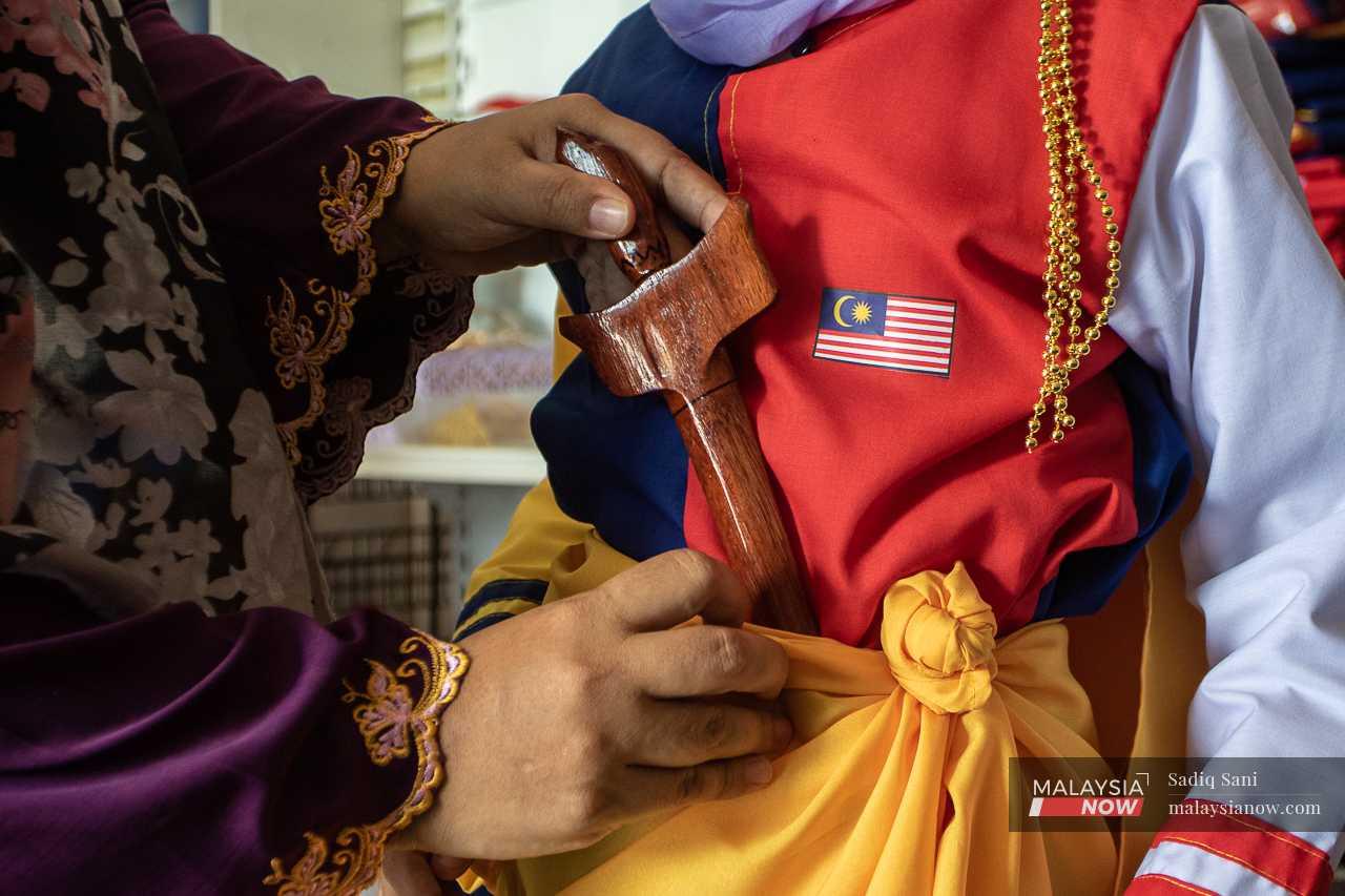 Helmaliza places a keris on a mannequin donning her custom-made Tun Fatimah outfit before showcasing it on her social media accounts.