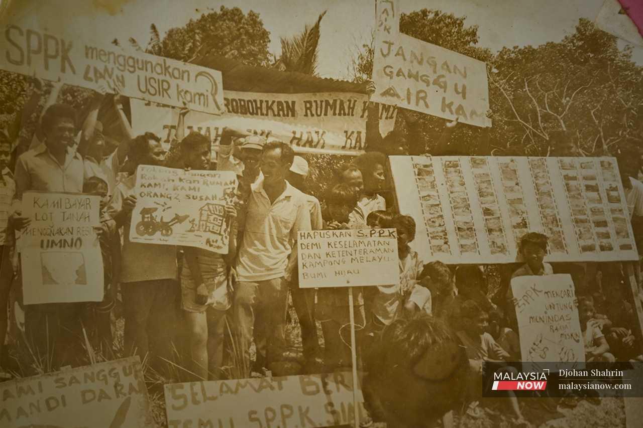 An archived image shows Rawiyah participating in a village demonstration, holding a protest banner against SPPK Sdn Bhd, after the developer cut off the water supply to their residences.