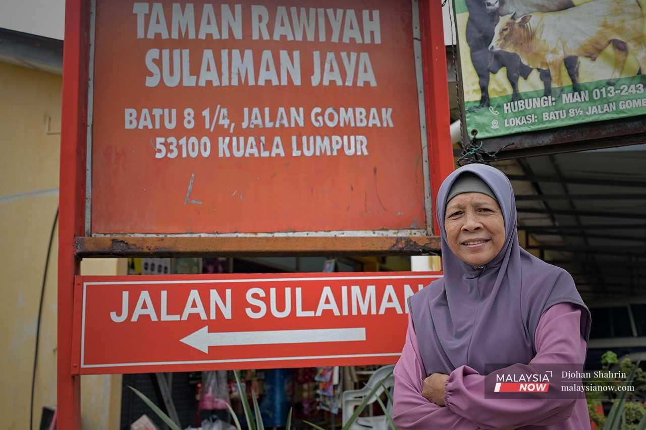 Rawiyah Kamil stands next to a signboard for Taman Rawiyah Sulaiman Jaya, a residential area named after her and her late husband, Sulaiman Yaakob, who worked to defend their land in their original home of Kampung Melayu Bumi Hijau, Setapak, in the 1980s and 90s.