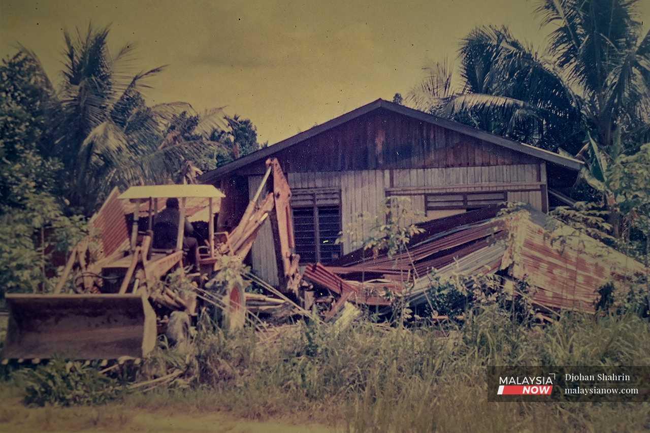 Heavy machinery tears down a house in Kampung Melayu Bumi Hijau.
