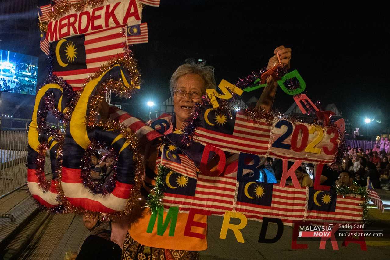 A woman holds up Merdeka-themed paraphernalia after walking from Maluri to Dataran Merdeka. 
