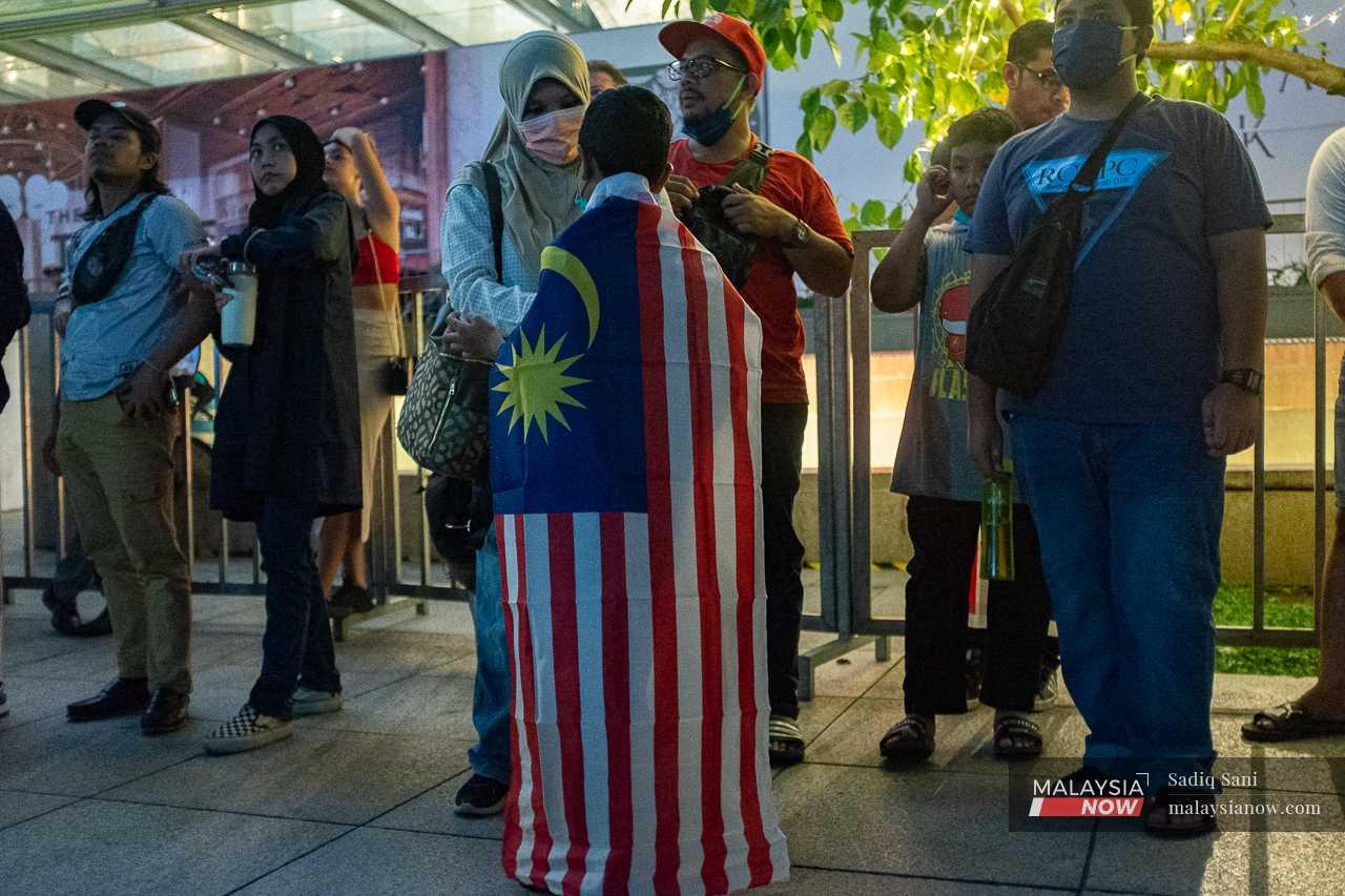 A woman wraps a flag around her son's shoulders. 