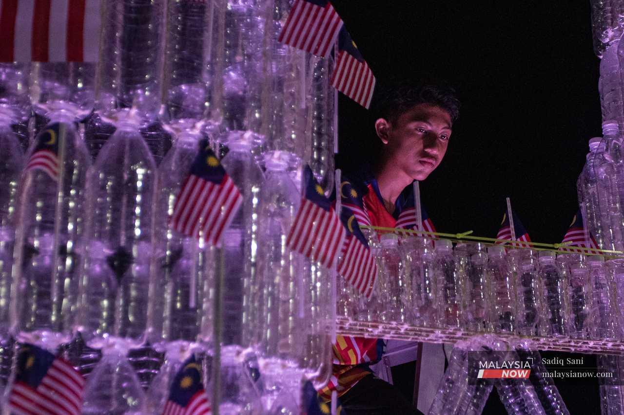 A youth builds a replica of the Kuala Lumpur Twin Towers using recycled water bottles in Tanjung Karang. 