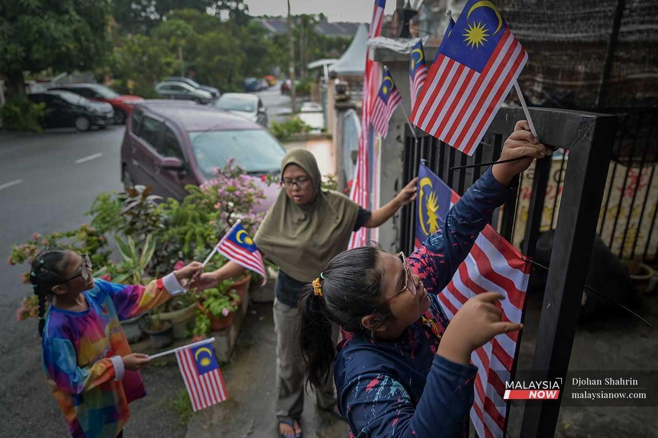 A family decorates their front gate with Malaysian flags in Taman Setia Fasa 2, Balakong.