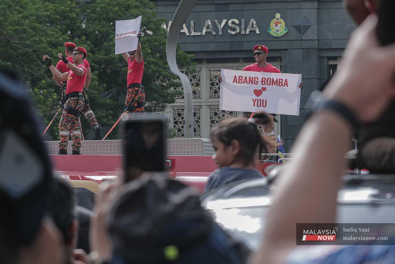 One of them holds up a sign reading 'Abang Bomba loves you' as others wave.