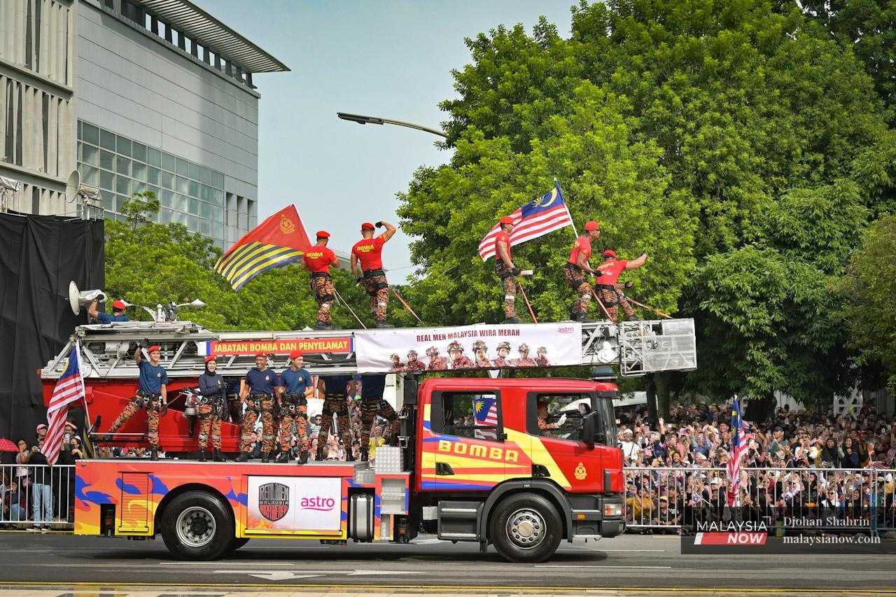 Fire and rescue personnel pose for the crowd as their fire engine rolls past.