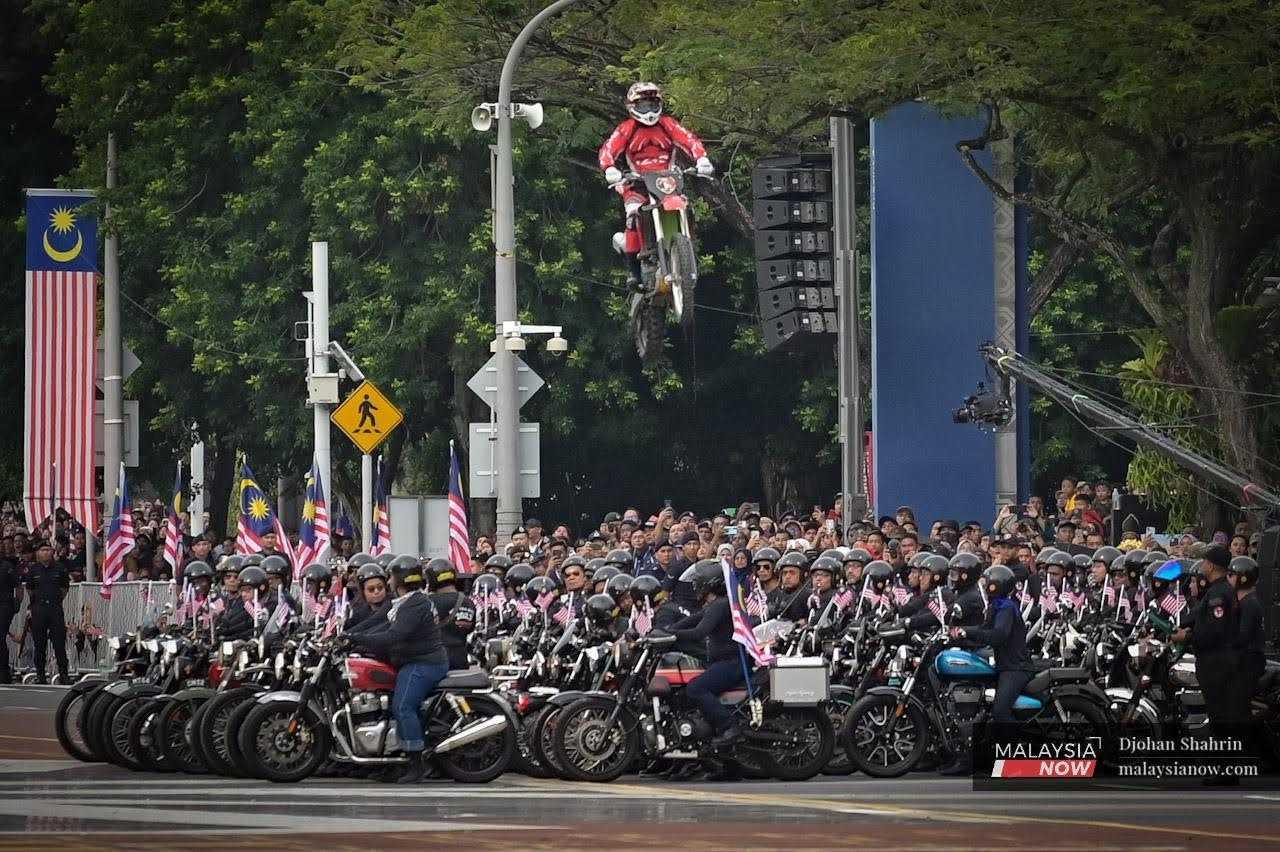 A motorcycle stuntman performs an acrobatic jump during the parade. 