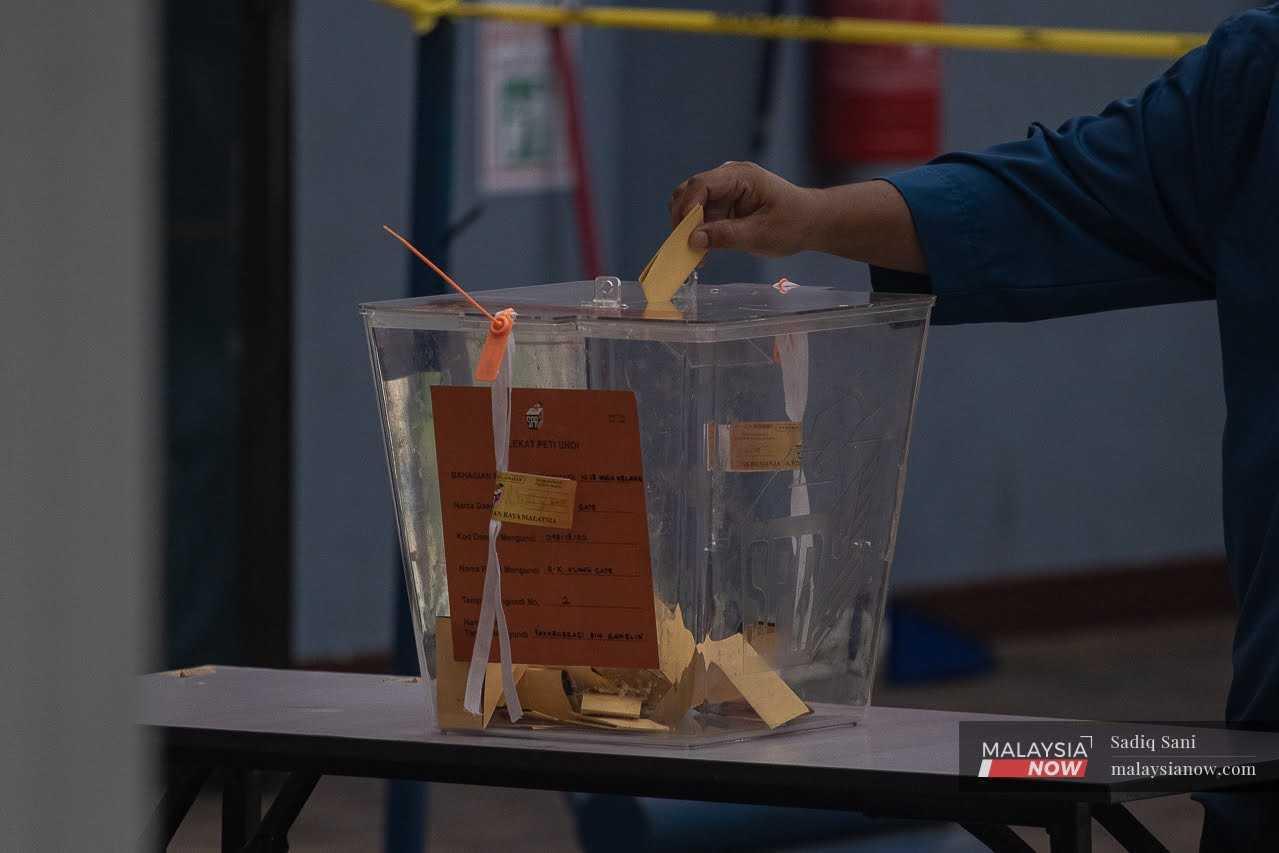 Gambar fail pengundi memasukkan kertas undi ke dalam peti undi yang disediakan di pusat mengundi di SK Klang Gate, 12 Ogos.