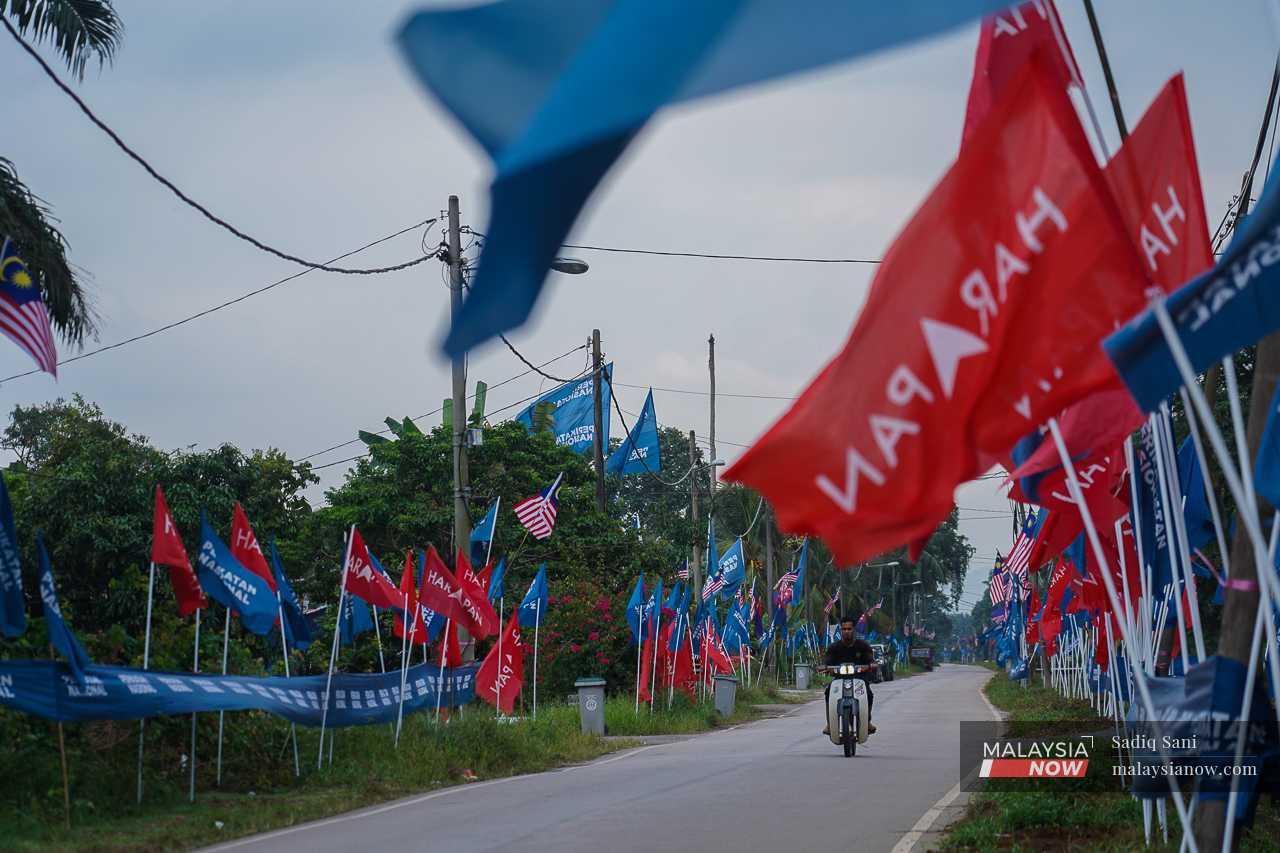 A motorcyclist passes an array of Pakatan Harapan and Perikatan Nasional flags in Simpang Jeram ahead of the by-election on Sept 9.