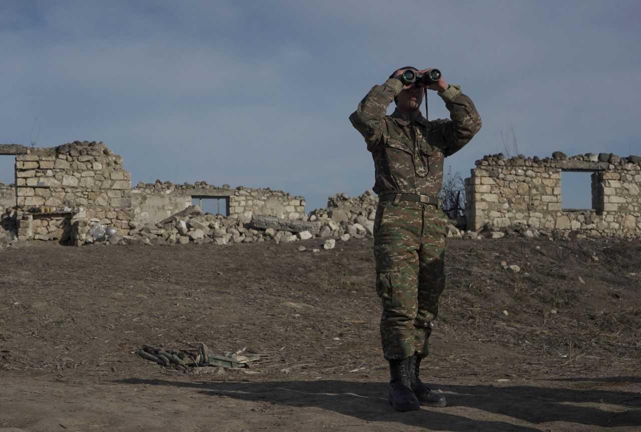 An ethnic Armenian soldier looks through binoculars as he stands at fighting positions near the village of Taghavard in the region of Nagorno-Karabakh, Jan 11, 2021. Photo: Reuters