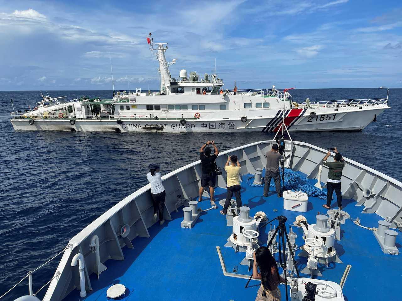 Journalists onboard a Philippines Coast Guard ship take photos of a China Coast Guard vessel, during a resupply mission for troops stationed at a grounded Philippines ship, in the South China Sea, Sept 8. Photo: Reuters