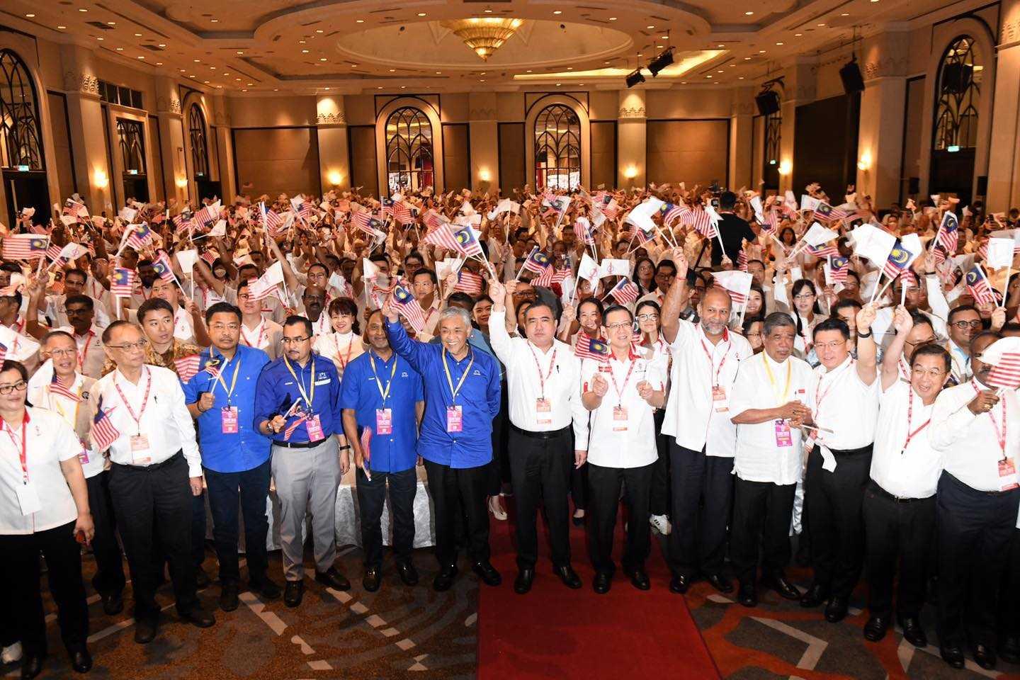 Pengerusi Barisan Nasional Ahmad Zahid Hamidi mengibarkan bendera bersama pemimpin DAP pada konvensyen 2023 parti itu. Gambar: Facebook
