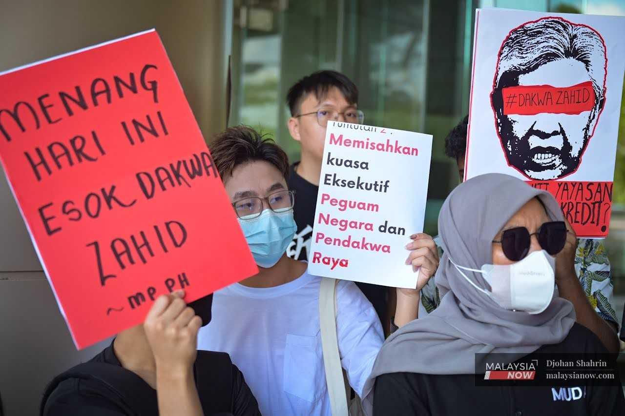 Plakat yang memaparkan grafik Timbalan Perdana Menteri Ahmad Zahid Hamidi dipegang di luar Jabatan Peguam Negara di Putrajaya ketika Muda dan Parti Sosialis Malaysia menyampaikan memorandum bantahan terhadap keputusan pembebasan beliau.