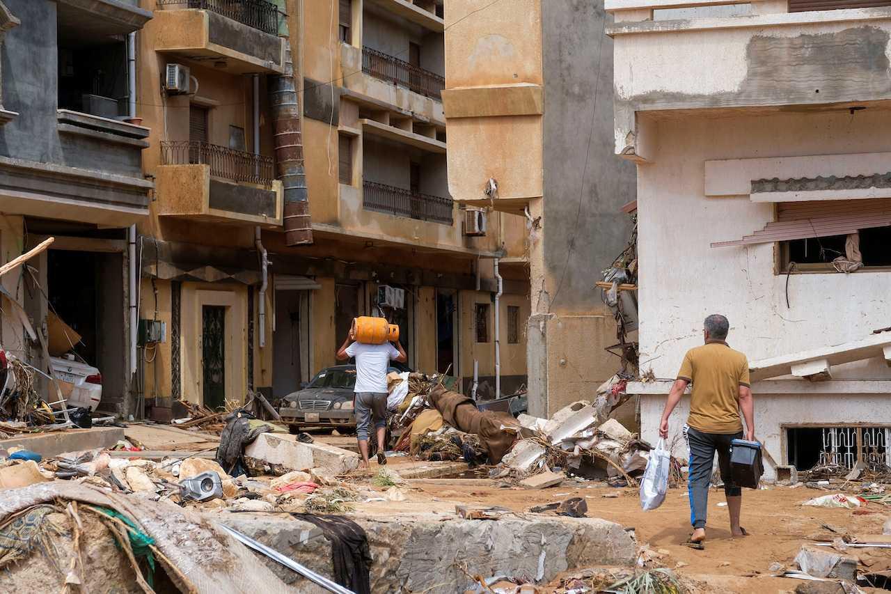 People walk between the debris after a powerful storm and heavy rainfall hit Libya, in Derna, Sept 12. Photo: Reuters