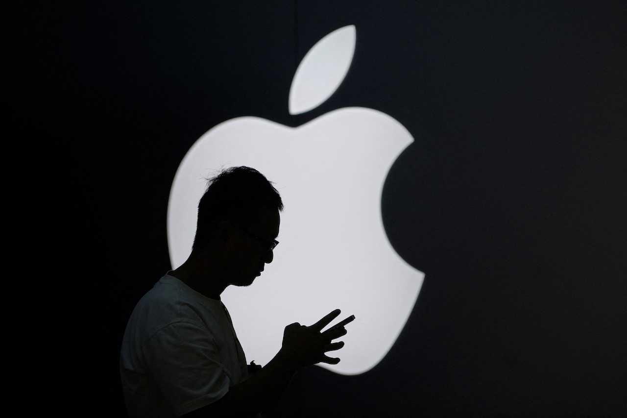 A man checks his phone near an Apple logo outside its store in Shanghai, China, Sept 13. Photo: Reuters