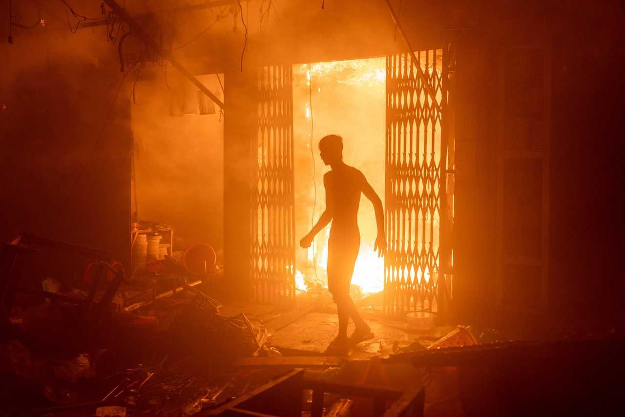 A person stands next to a burning building after a fire broke out at the Mohammadpur Krishi market, in Dhaka, Bangladesh, Sept 14, in this picture obtained from social media. Photo: Reuters