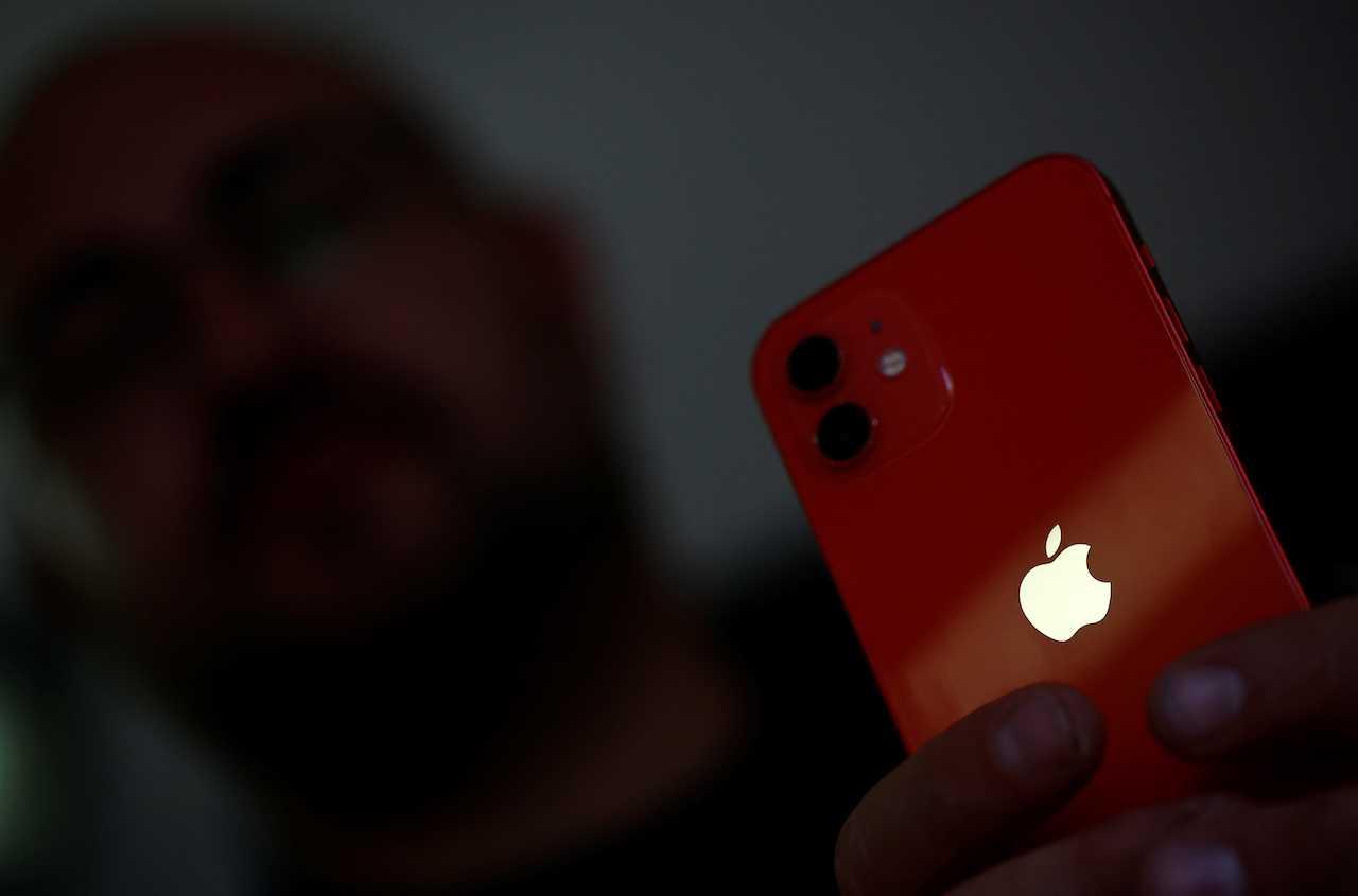 A man poses with an Apple iPhone 12 in a mobile phone store in Nantes, France, Sept 13. Photo: Reuters
