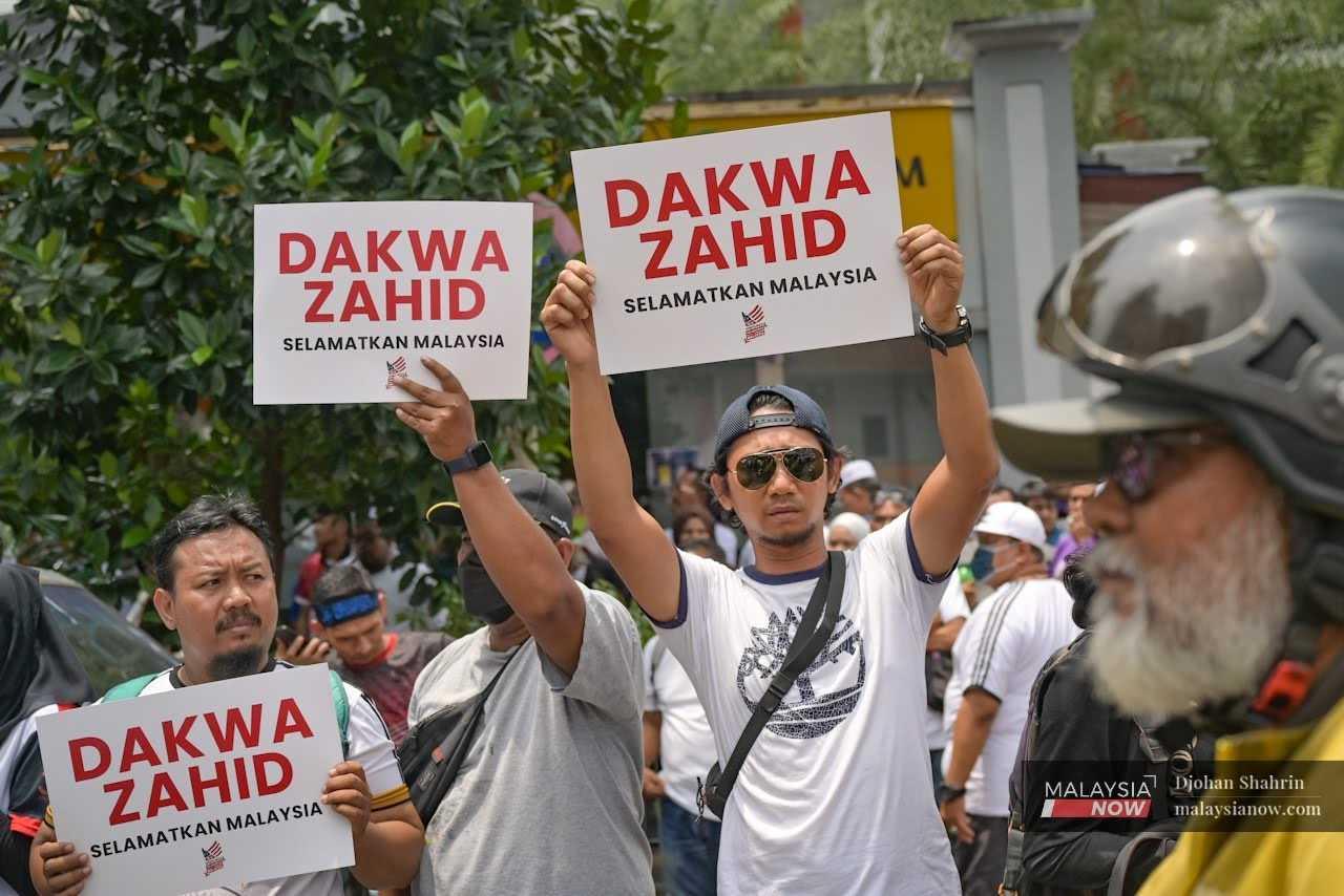 More placards calling for Zahid's prosecution are held up in the crowd.
