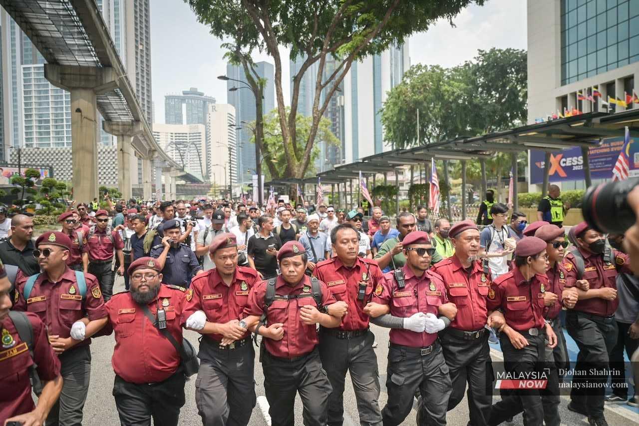 Members of the PAS crowd control unit escort the participants of the 'Save Malaysia' rally as they move from Kampung Baru to the Dang Wangi police headquarters to lodge a police report in Kuala Lumpur, Sept 16.  