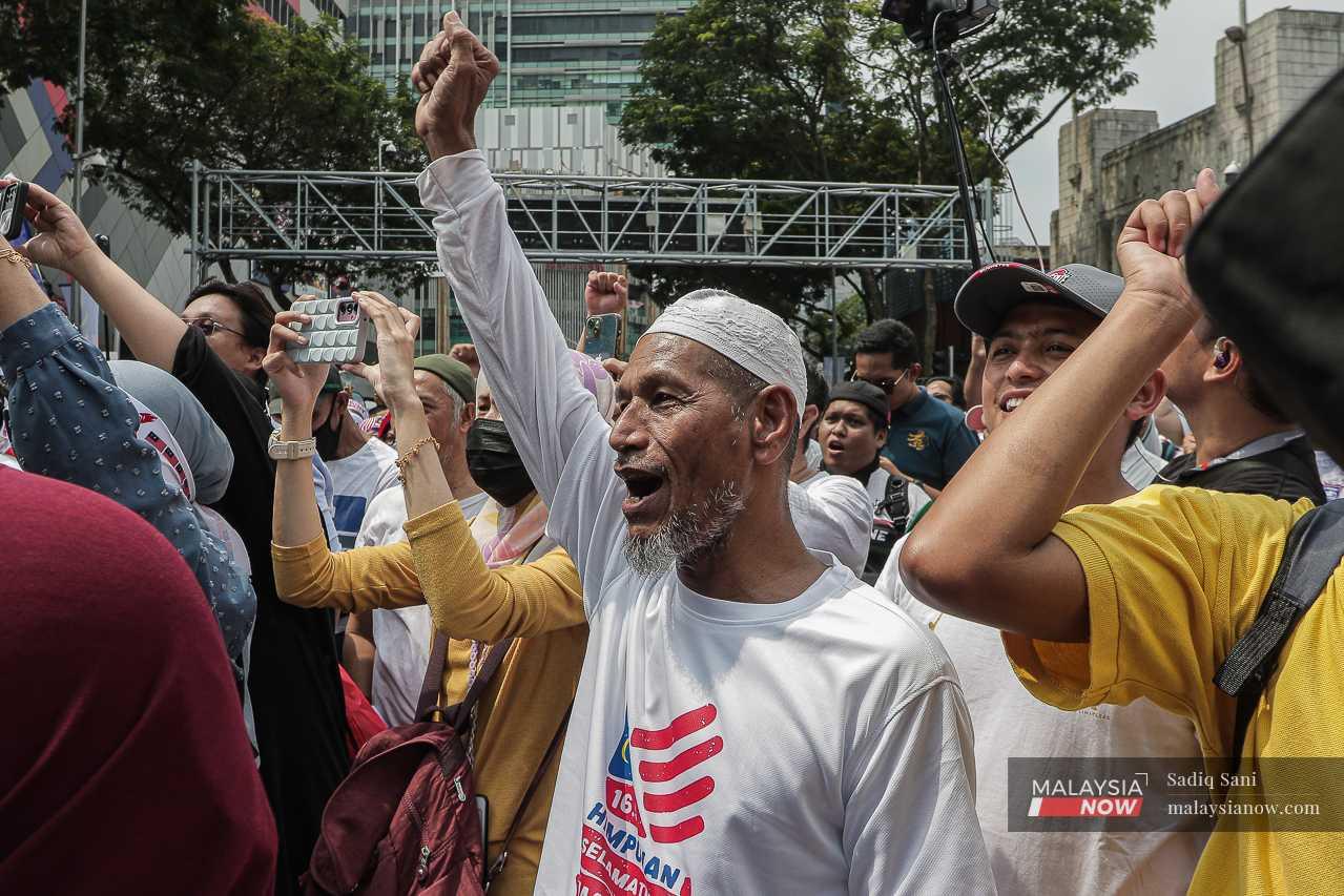 Seorang penunjuk perasaan mengangkat tangan dengan isyarat penumbuk sambil melaungkan slogan di luar kompleks beli-belah Sogo. 